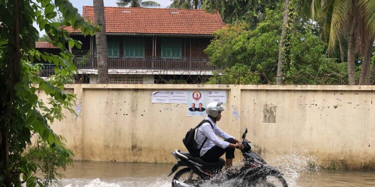 ទិដ្ឋភាពពលរដ្ឋជិះម៉ូតូកាត់ទឹកលើកំណាត់ផ្លូវ៦៩បេតេ(69BT) ក្នុងសង្កាត់បឹងទំពន់២ ខណ្ឌមានជ័យ រាជធានីភ្នំពេញកាលពីថ្ងៃទី៧ ខែកក្កដា ឆ្នាំ២០២៣។ (លោក សុត បាន)