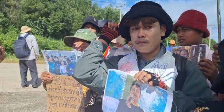 កូនប្រុសអ្នកស្រី ផាវ ញ៉ើង កាន់រូបថតម្តាយនឹងដៃ រួមជាមួយពលរដ្ឋប្រមាណ២០០នាក់ទៀតមកពីសហគមន៌មកពីរនៃ ស្រុកស្រែអំបិល និងស្រុកបុទុមសាគរ ខេត្តកោះកុង ដោយនាំគ្នាអង្គុយខាងមុខសាលាឧទ្ធរណ៍តំបន់ព្រះសីហនុ នៅព្រឹកថ្ងៃទី៥ ខែតុលា ឆ្នាំ២០២៣ ទាមទាឱ្យដោះលែងដោយគ្មានលក្ខខណ្ឌ និងទម្លាក់ការចោទប្រកាន់ទៅលើ អ្នកស្រី ផាវ ញ៉ើង និងអ្នកស្រី សេង លីន។ (ហ្វេសប៊ុក សហគមន៍ជីខក្រោម ខេត្តកោះកុង)