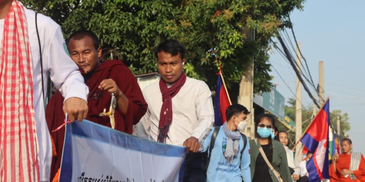 លោក កើត សារ៉ាយ (បង់កក្រមាក្រហម) កាន់បដានៅកណ្តាលកំពុងដើរធម្មយាត្រាក្នុងរាជធានីភ្នំពេញផ្សាយមេត្តាចិត្តផ្សារភ្ជាប់នឹងសិទ្ធិមនុស្ស ក្រោមប្រធានបទ ធានាសេចក្តីថ្លៃថ្នូរ សេរីភាព និងយុត្តិធម៌ដល់ពលរដ្ឋគ្រប់រូប កាលពីថ្ងៃទី១០ ខែធ្នូ ឆ្នាំ២០២៣។ (រូបភាព៖ ផ្តល់ឱ្យ)