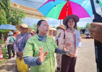 អ្នកស្រី ផាវ ញ៉ើង (ស្រីពាក់មូក ក្រោមឆ័ត្រ) និងសហគមន៍មានវិវាទដីធ្លីនៅខេត្តកោះកុងផ្សេងទៀត ថតនៅមុខអយ្យការអមសាលាដំបូងខេត្តកោះកុង នៅឆ្នាំ២០២៤។ (ផ្តល់ឱ្យ)