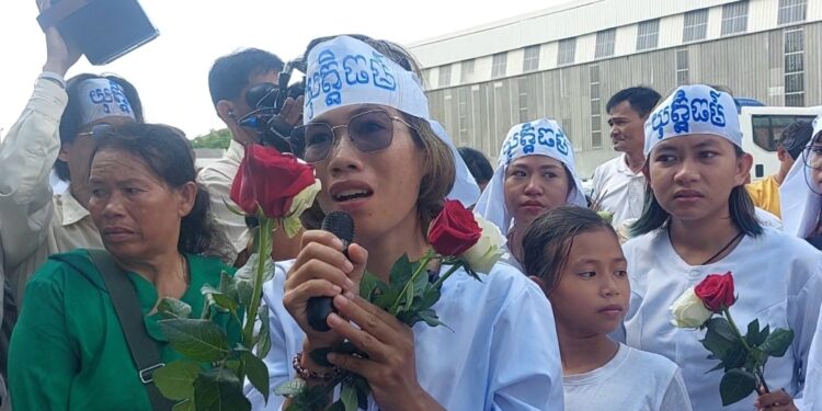 សកម្មភាពរបស់សមាជិកក្រុមមាតាធម្មជាតិម្នាក់ កញ្ញា ឡុង គន្ធា ដែលបានកាន់ផ្កាកូលាប និងមីក្រូហ្វូន ថ្លែងមុនពេលចាប់ខ្លួននៅក្បែរសាលាដំបូងរាជធានីភ្នំពេញកាលពីថ្ងៃទី២ ខែកក្កដា ឆ្នាំ២០២៤។ (លោក ឃាង សុខមាន)