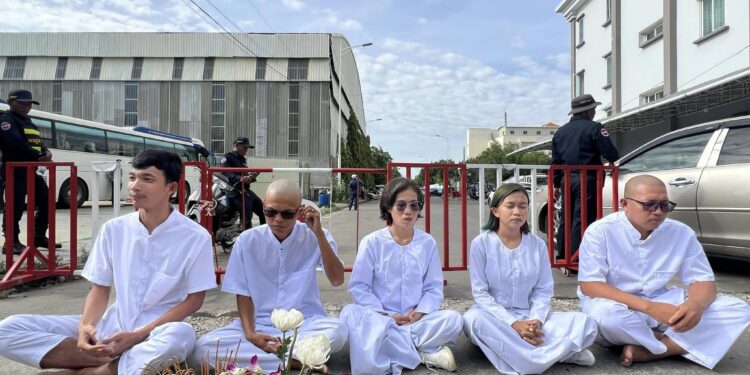 សកម្មជនចលនាមាតាធម្មជាតិ ៥នាក់(ពីឆ្វេងទៅស្តាំ រួមមានលោក លី ចាន់ដារ៉ាវុត លោក ថុន រដ្ឋា កញ្ញា ឡុង គន្ធា កញ្ញា ភួន កែវរស្មី និងលោក យឹម លាងហ៊ី) កំពុងអង្គុយសមាធិនៅខាងមុខសាលាដំបូងរាជធានីភ្នំពេញ កាលពីថ្ងៃទី៥ ខែមិថុនា ឆ្នាំ២០២៤។ (Facebook; Mother Nature Cambodia)